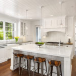 White Kitchen Interior with Island, Sink, Cabinets, and Hardwood Floors in New Luxury Home